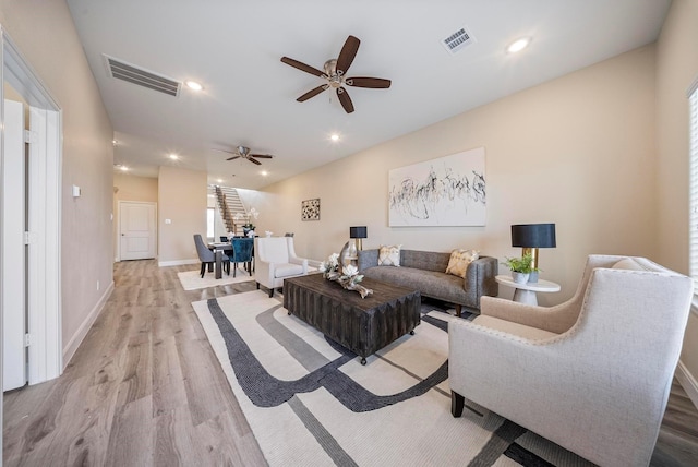 living area featuring baseboards, a ceiling fan, light wood-type flooring, and visible vents