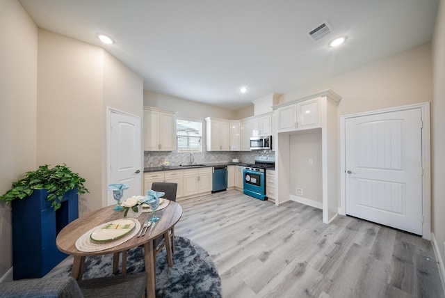 kitchen with visible vents, dark countertops, a sink, light wood-style flooring, and appliances with stainless steel finishes