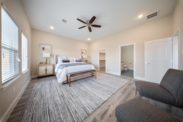 bedroom with baseboards, a walk in closet, visible vents, and light wood-style flooring