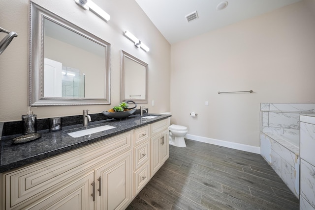 full bath with double vanity, wood finished floors, toilet, baseboards, and a sink