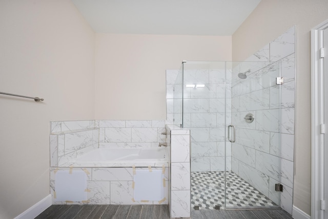 bathroom with wood finished floors, a stall shower, baseboards, and a bath