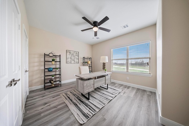 office area with baseboards, a ceiling fan, light wood-style flooring, and visible vents