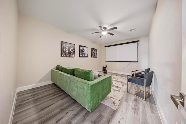 cinema room featuring baseboards, a ceiling fan, wood finished floors, and visible vents