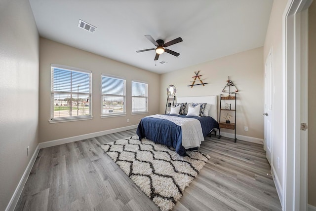 bedroom with visible vents, light wood-style flooring, baseboards, and ceiling fan
