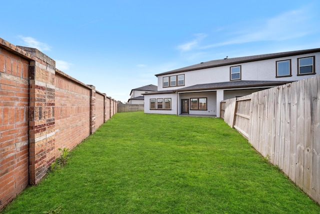 back of property featuring a fenced backyard, stucco siding, and a yard