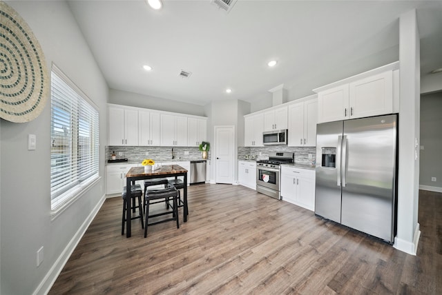 kitchen with tasteful backsplash, stainless steel appliances, dark wood-style flooring, and visible vents