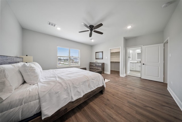 bedroom with a walk in closet, visible vents, dark wood finished floors, baseboards, and recessed lighting