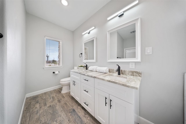 bathroom with a sink, baseboards, toilet, and wood finished floors