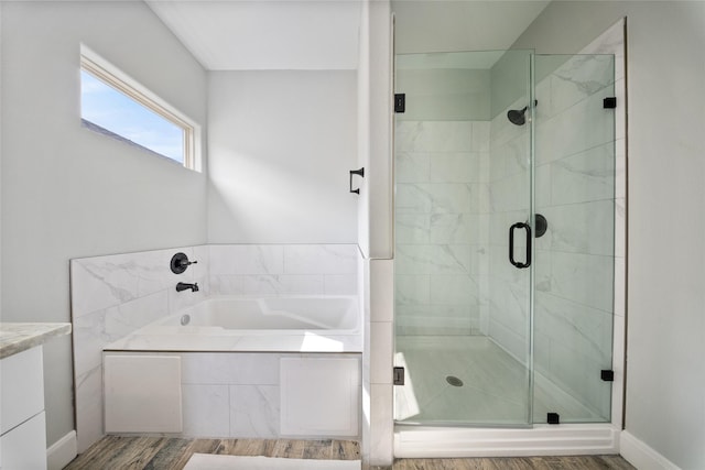 bathroom featuring wood finished floors, a bath, and a stall shower