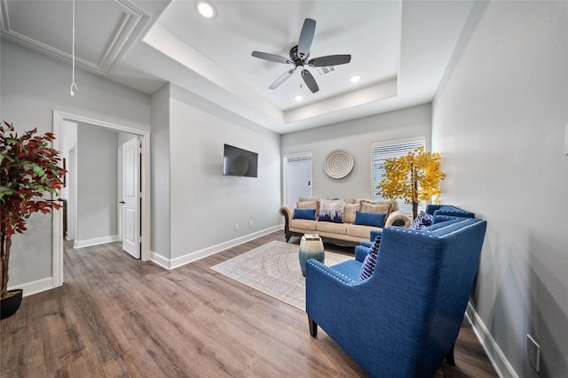 living room featuring attic access, a ceiling fan, baseboards, wood finished floors, and a tray ceiling