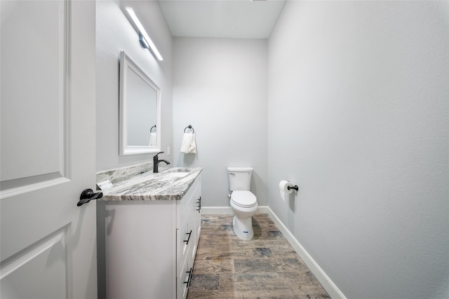 bathroom featuring vanity, baseboards, wood finished floors, and toilet