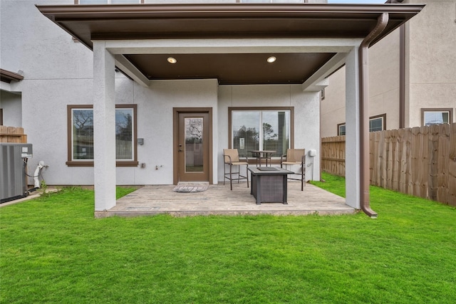 rear view of house featuring a patio, a lawn, fence, and stucco siding
