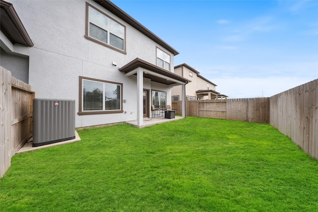 back of house featuring stucco siding, a fenced backyard, a patio area, central air condition unit, and a lawn
