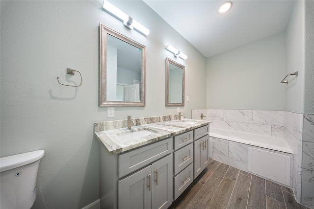 bathroom with a garden tub, a sink, double vanity, and toilet