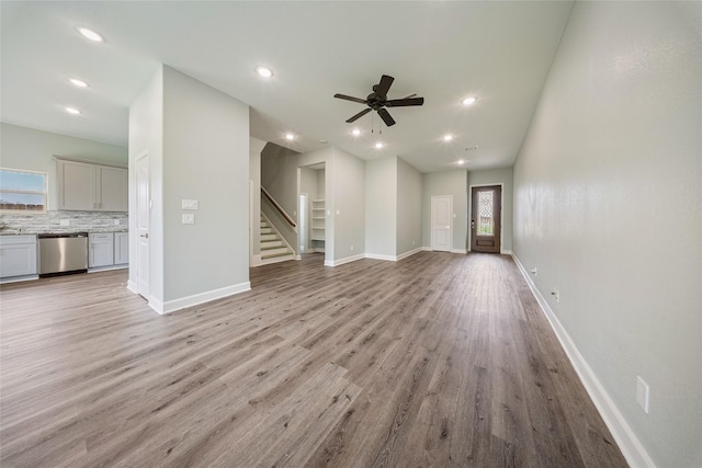 unfurnished living room with recessed lighting, light wood-style flooring, stairs, and ceiling fan