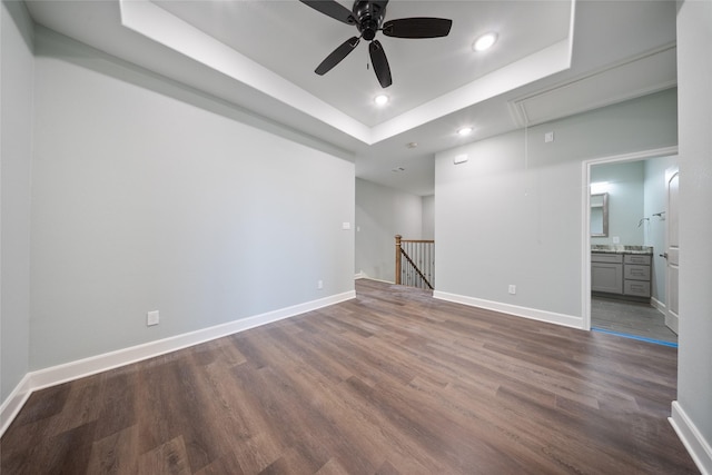 spare room with dark wood-style flooring, attic access, recessed lighting, a tray ceiling, and a ceiling fan