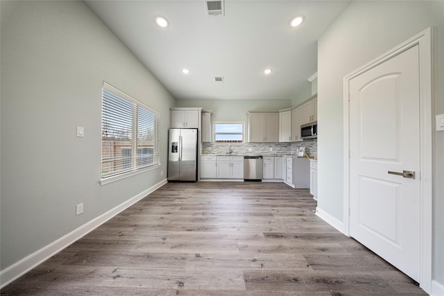 kitchen featuring a sink, light countertops, stainless steel appliances, tasteful backsplash, and visible vents