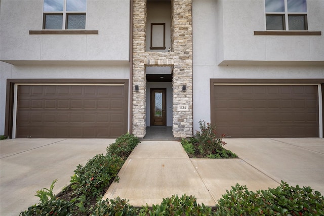 townhome / multi-family property featuring a garage, stucco siding, and stone siding