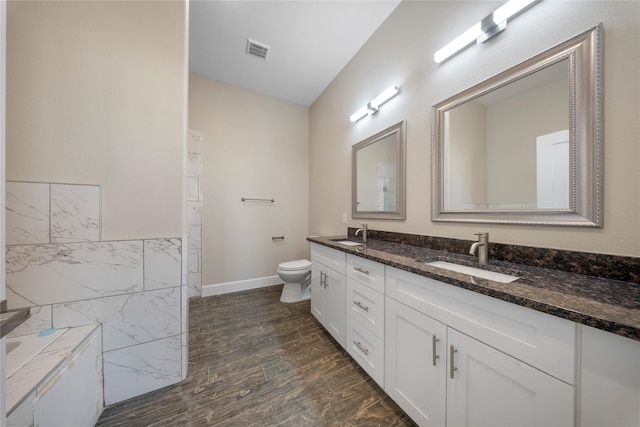 bathroom featuring double vanity, toilet, visible vents, and a sink