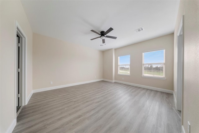 empty room with baseboards, a ceiling fan, light wood finished floors, and visible vents