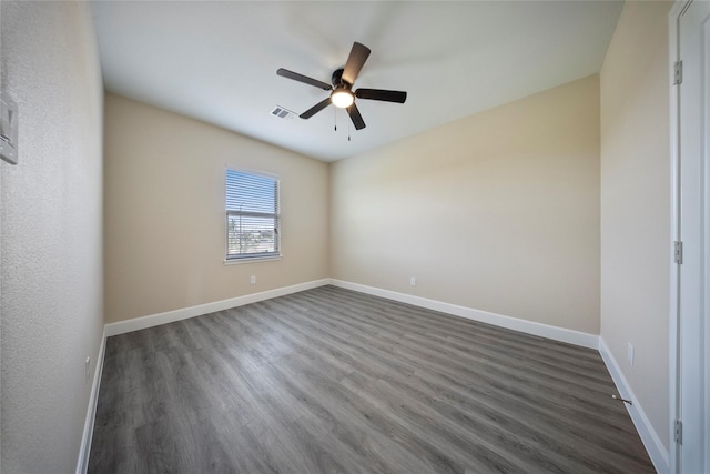 empty room featuring dark wood-type flooring, a ceiling fan, baseboards, and visible vents