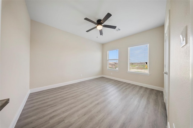 spare room featuring baseboards, ceiling fan, wood finished floors, and visible vents