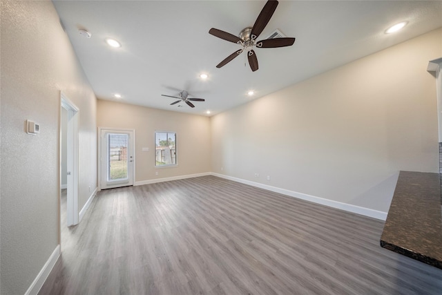 unfurnished living room with a ceiling fan, baseboards, recessed lighting, and wood finished floors