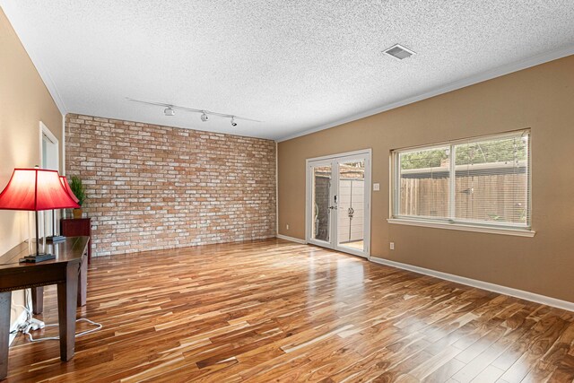 3749 Wakeforest St, Houston, TX 77098 - empty room featuring brick wall, wood finished floors, a textured ceiling, crown molding, and baseboards