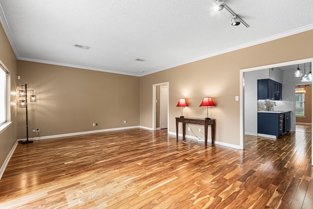 3749 Wakeforest St, Houston, TX 77098 - unfurnished living room with a textured ceiling, wood finished floors, a sink, rail lighting, and crown molding