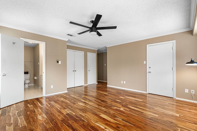 3749 Wakeforest St, Houston, TX 77098 - unfurnished bedroom featuring crown molding, wood finished floors, two closets, a textured ceiling, and ensuite bath