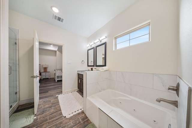 ensuite bathroom featuring vanity, a tub with jets, wood finished floors, visible vents, and a stall shower