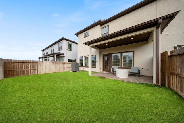 rear view of property with central AC, a fenced backyard, and stucco siding