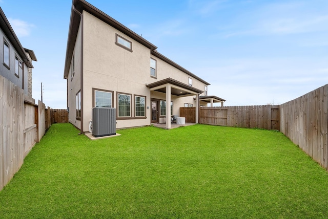 back of property featuring a fenced backyard, stucco siding, a lawn, and central AC