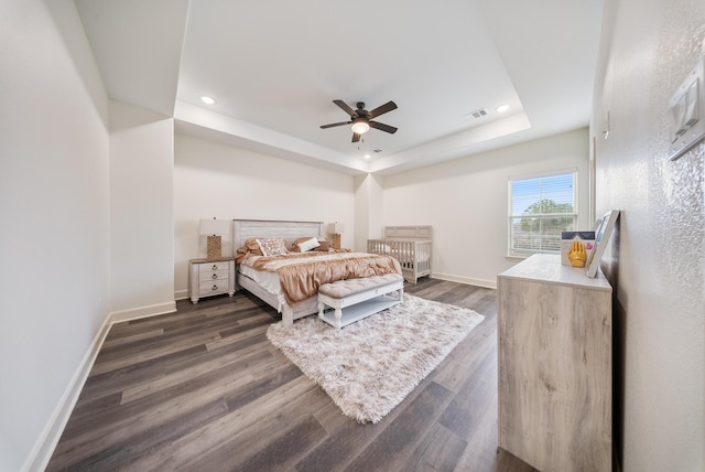 bedroom with visible vents, baseboards, a tray ceiling, recessed lighting, and dark wood-type flooring