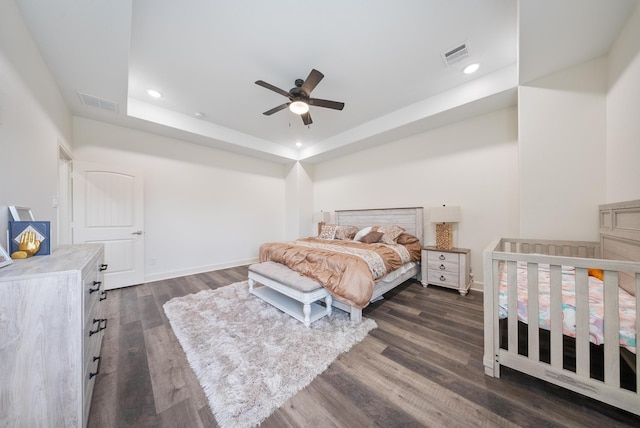 bedroom featuring recessed lighting, a raised ceiling, dark wood-style flooring, and visible vents