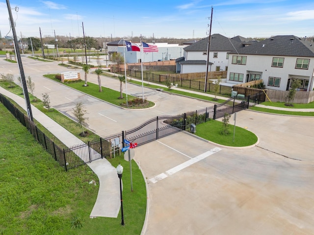 surrounding community with a residential view, fence, uncovered parking, and a gate