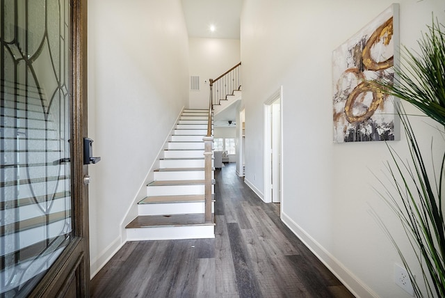 entrance foyer with visible vents, wood finished floors, baseboards, a high ceiling, and stairway