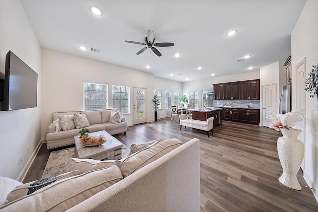 living room featuring a ceiling fan, baseboards, visible vents, and dark wood-type flooring