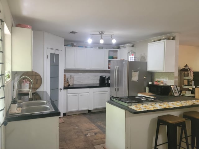 kitchen featuring tasteful backsplash, open shelves, a sink, white cabinets, and freestanding refrigerator