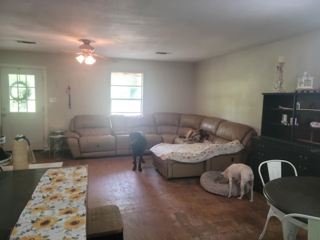 living room with ceiling fan, visible vents, and a wealth of natural light