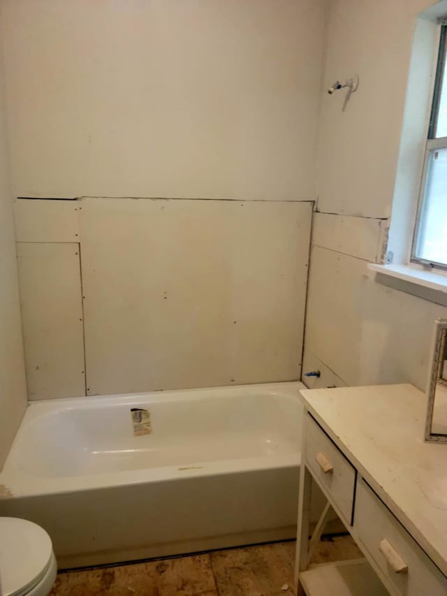 bathroom featuring vanity, toilet, and a tub to relax in