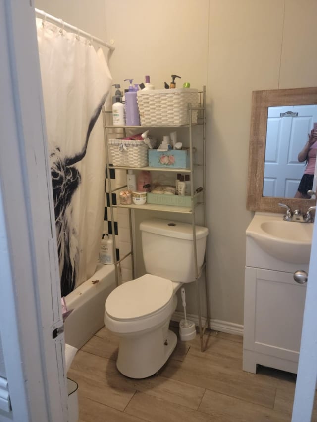 bathroom featuring vanity, toilet, shower / bath combination with curtain, baseboards, and wood finished floors