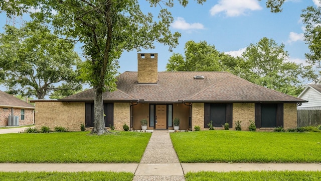 ranch-style home featuring roof with shingles, a chimney, and a front lawn