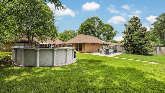 rear view of property featuring a patio area, an outdoor pool, fence, and a yard