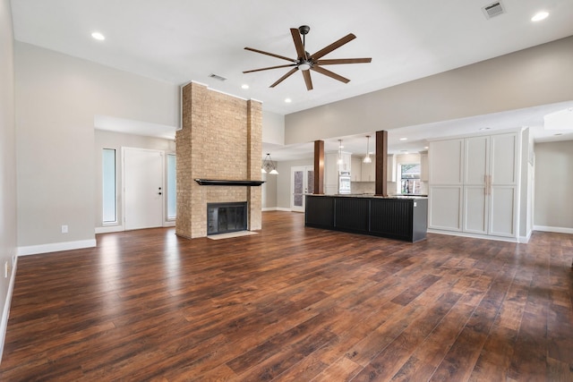 unfurnished living room with ceiling fan, a fireplace, dark wood-type flooring, and visible vents