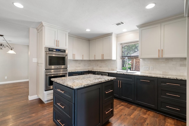 kitchen with a kitchen island, visible vents, a sink, baseboards, and stainless steel appliances