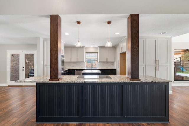 kitchen with decorative backsplash, light stone countertops, a spacious island, a sink, and stainless steel appliances