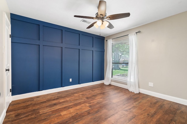 spare room featuring visible vents, a ceiling fan, baseboards, and dark wood-type flooring