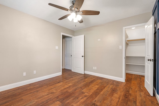 unfurnished bedroom featuring ceiling fan, baseboards, wood finished floors, a spacious closet, and a closet