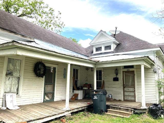 back of house with roof with shingles and a porch